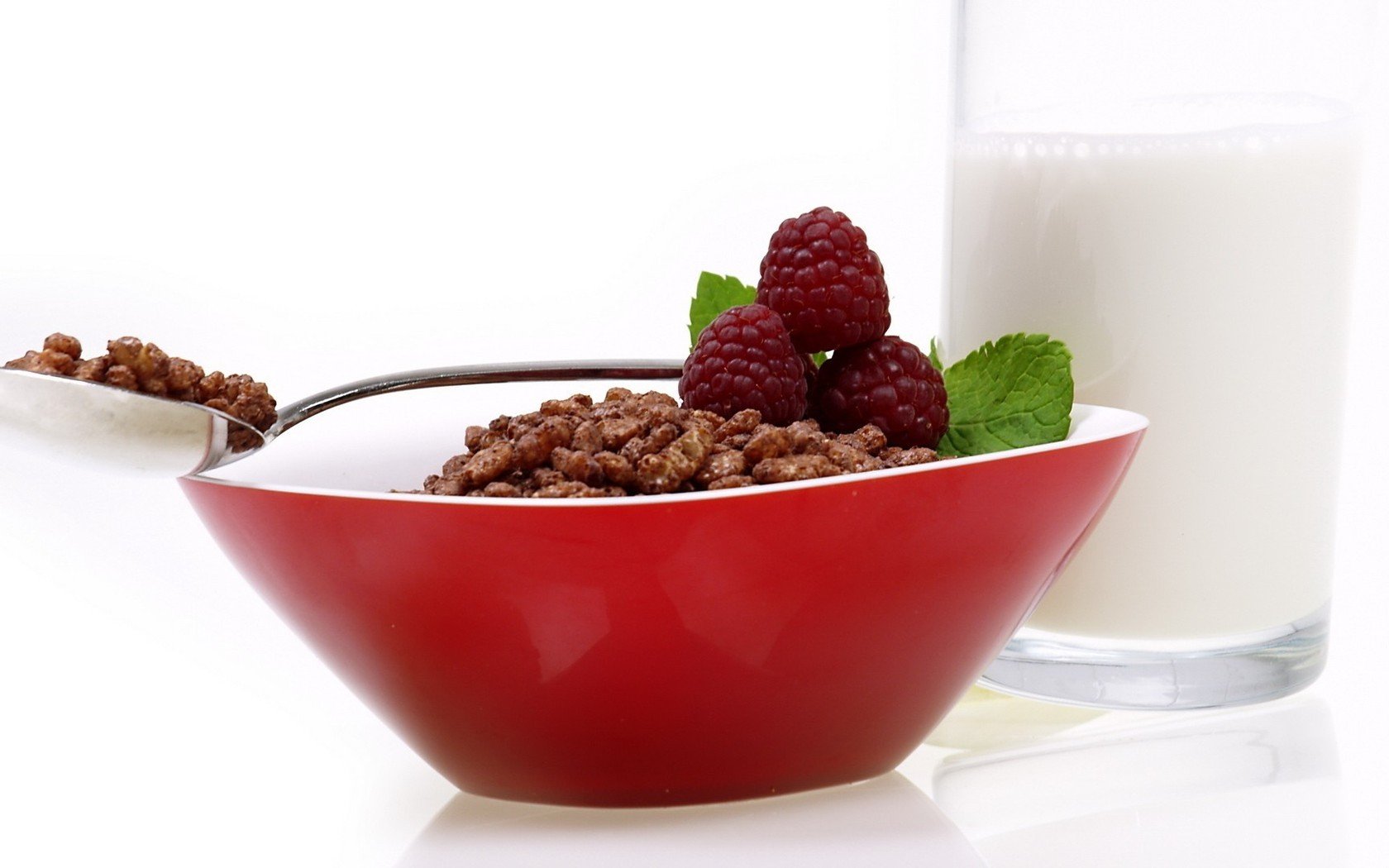 HD PC desktop wallpaper/background: red bowl of chocolate cereal topped with raspberries and mint, spoonful beside it and a glass of milk on a white background.
