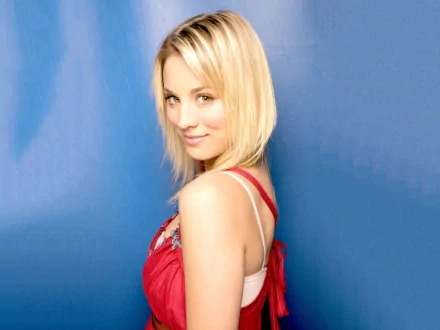 HD desktop wallpaper featuring Kaley Cuoco, showcasing her smiling profile against a vibrant blue background. A stylish and captivating image for any fan.