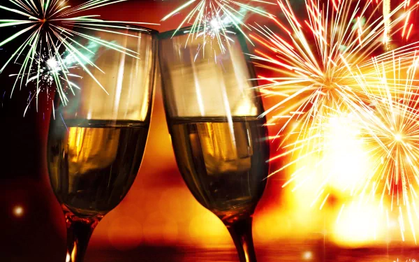 4K Ultra HD desktop wallpaper featuring two champagne glasses clinking amid vibrant New Year holiday fireworks bursting in the night sky.