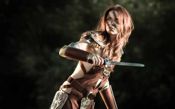 A fierce woman in elaborate cosplay poses with a sword, showcasing her detailed costume against a blurred natural background. This HD image makes an impactful desktop wallpaper.