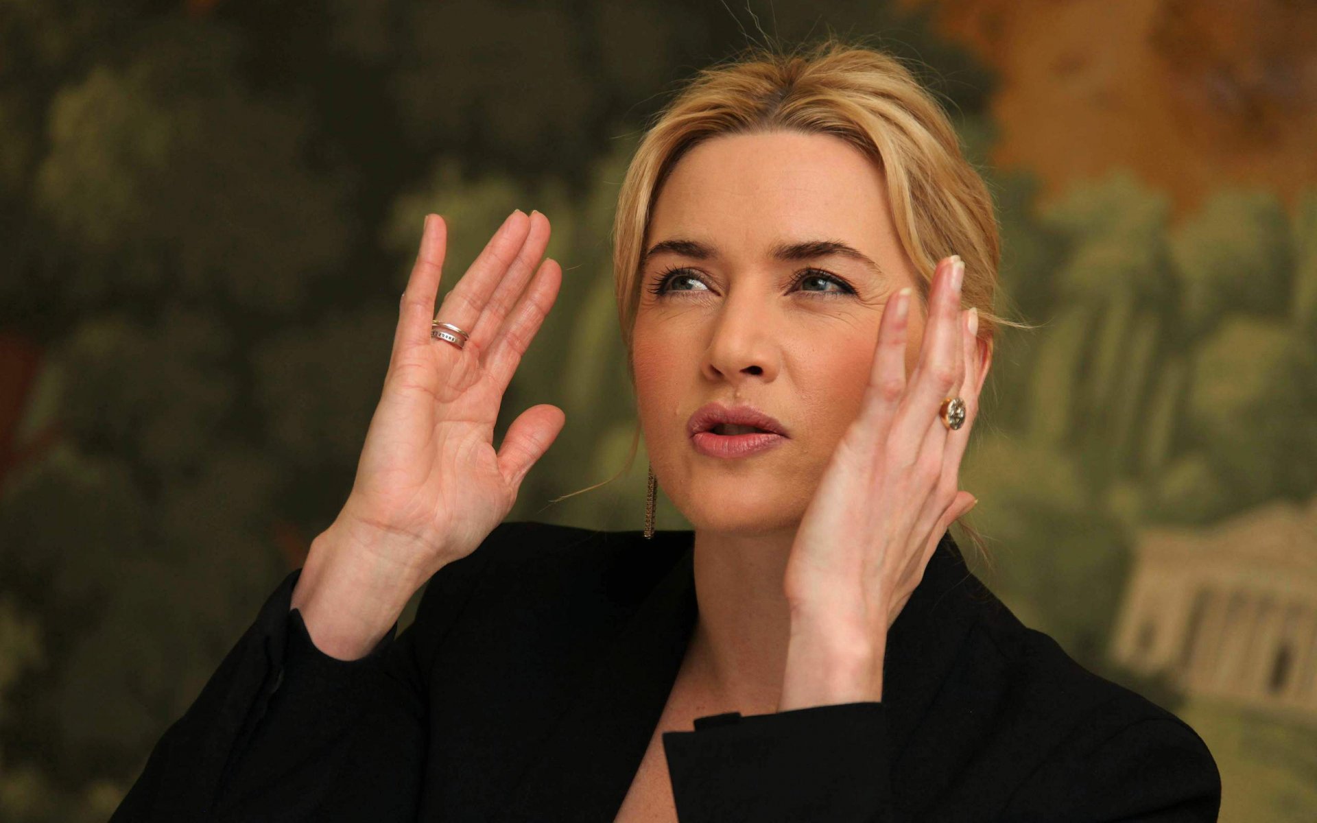 HD PC desktop wallpaper of celebrity Kate Winslet gesturing with her hands against a blurred artistic background.
