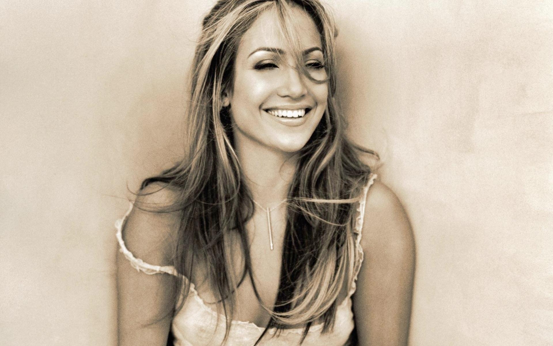 Sepia-toned HD PC desktop wallpaper of a smiling woman with long hair in a sleeveless top, relaxed pose against a soft, textured neutral background.