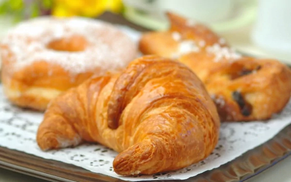 HD PC desktop wallpaper featuring freshly baked croissants and pastries arranged on a tray, highlighting the art of baking and delicious food.