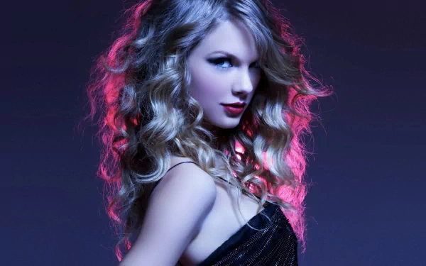 A high-definition desktop wallpaper featuring a blonde woman, tagged as Taylor Swift, set against a dark background with soft, colorful lighting highlighting her flowing hair and stylish attire.