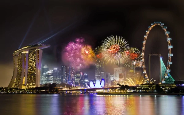 A stunning HD desktop wallpaper featuring vibrant fireworks over a city skyline, showcasing iconic landmarks like the Marina Bay Sands and the Singapore Flyer at night.