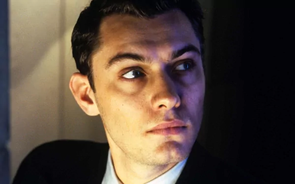 HD desktop wallpaper featuring a still from Gattaca with a focused man in suit looking upwards, posed against a dark background.