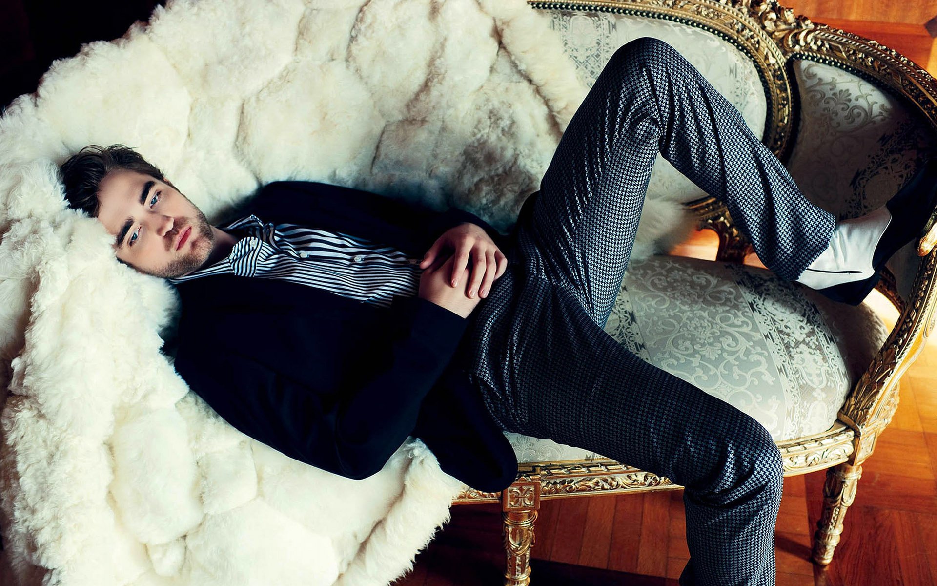 A stylish Robert Pattinson lounges on an ornate couch, exuding charm in this high-definition desktop wallpaper, showcasing his relaxed yet sophisticated vibe.