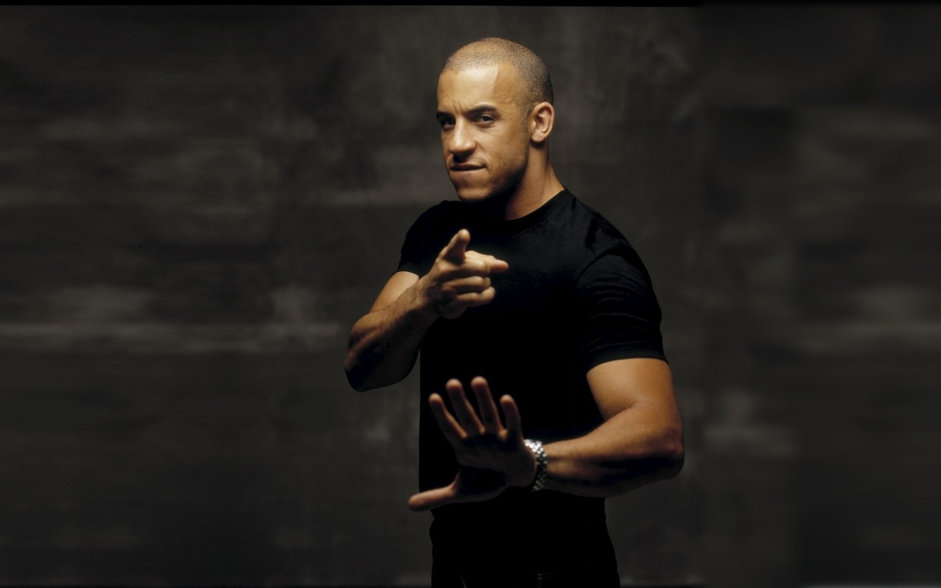 HD PC desktop wallpaper featuring celebrity Vin Diesel in a black shirt striking a confident pose against a dark background.