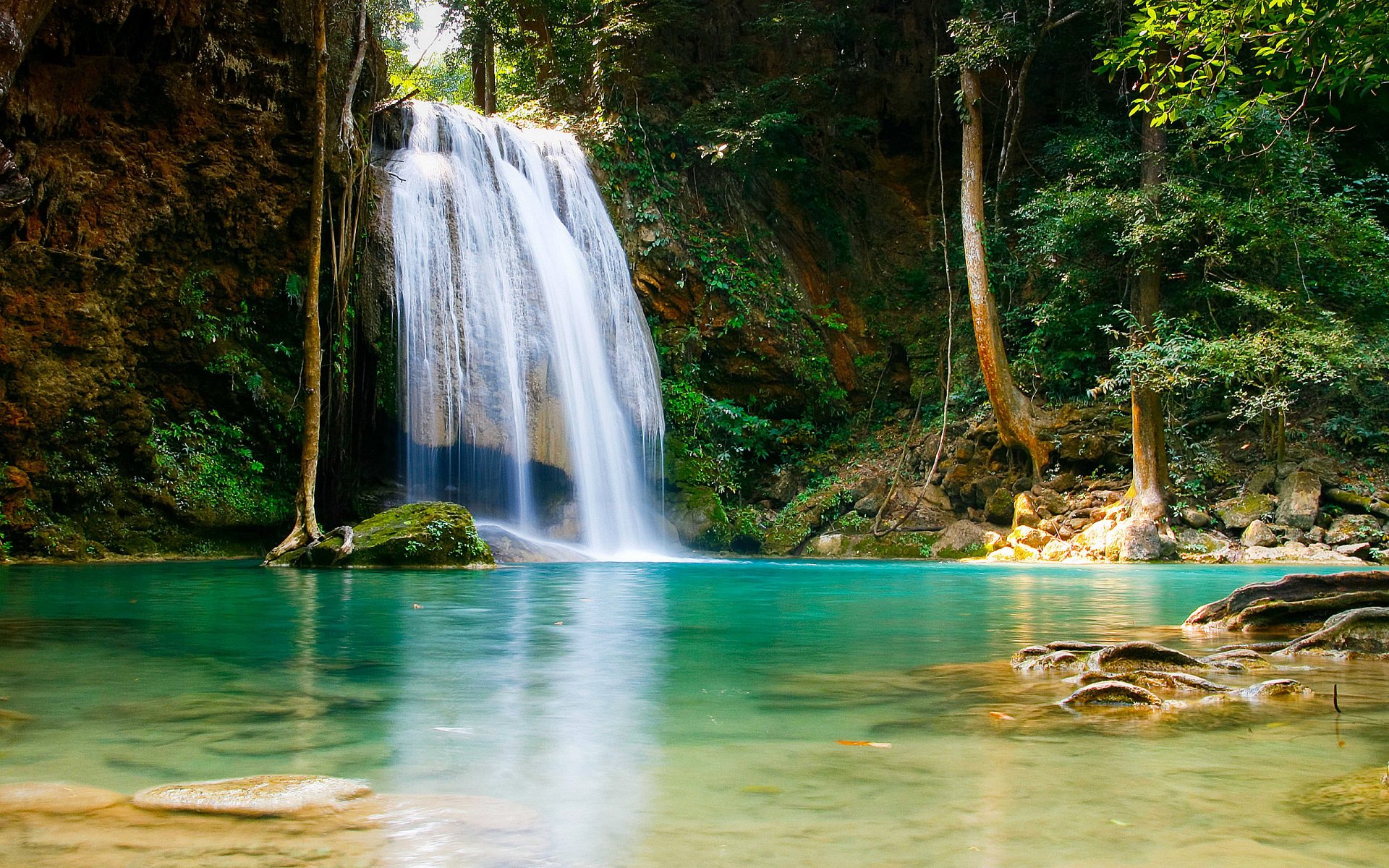 HD PC desktop wallpaper showcasing a serene waterfall cascading into a clear turquoise pool surrounded by lush green forest in a natural setting.