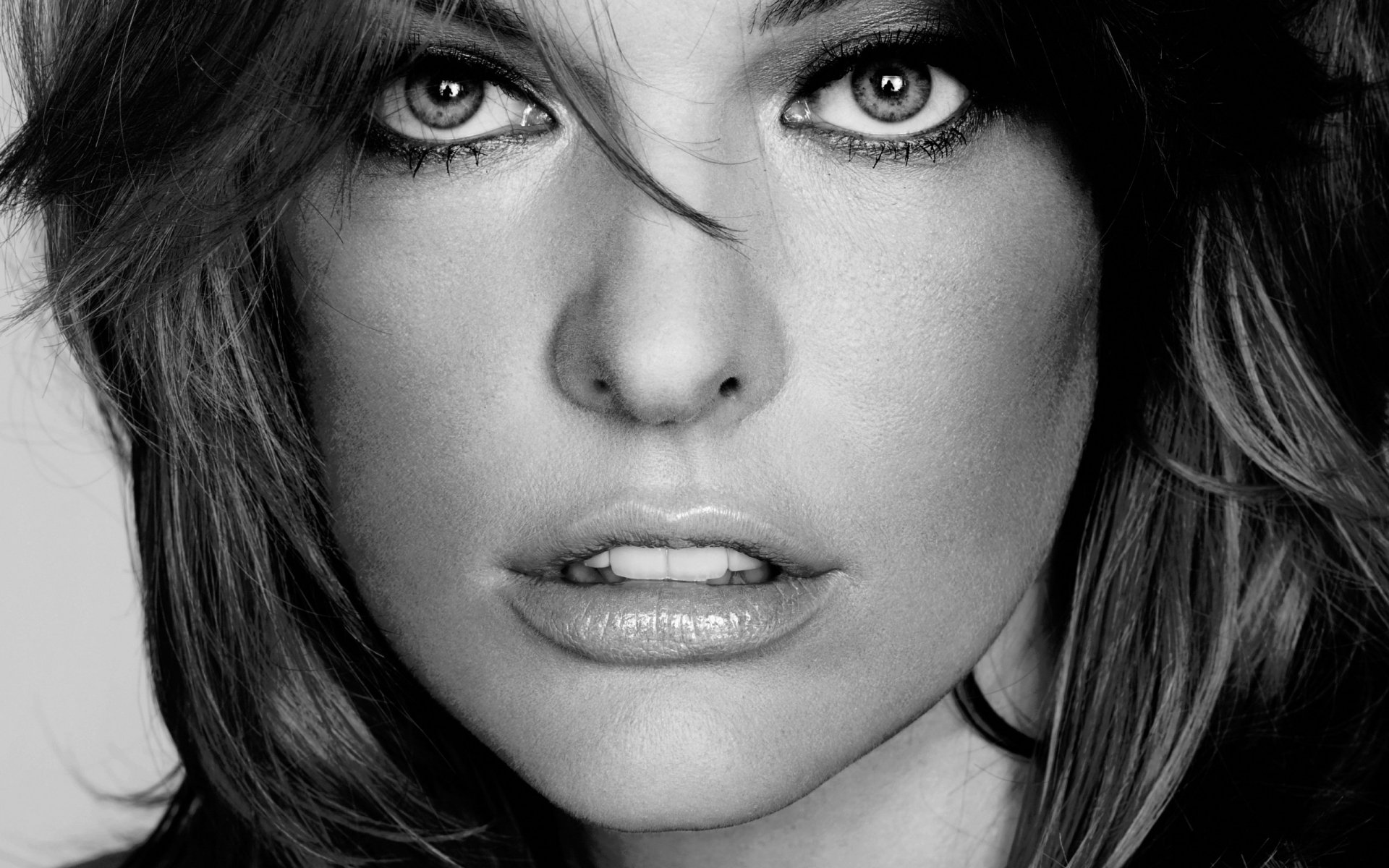 Black and white HD wallpaper featuring celebrity Milla Jovovich, showcasing her striking features and intense gaze. A captivating background for any desktop.