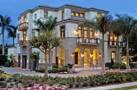 HD desktop wallpaper featuring a grand, illuminated multi-story house with palm trees, lush landscaping, and a twilight sky background.
