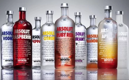 HD PC desktop wallpaper/background featuring a row of man-made Absolut vodka bottles in assorted flavors and colors on a reflective surface.