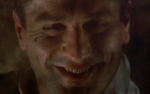 Close-up of a grinning man in dim light; moody HD desktop wallpaper evoking the gritty gangster atmosphere of Once Upon a Time in America.