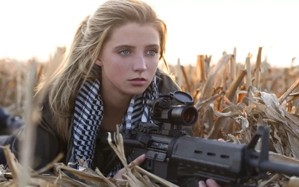 A focused woman in a cornfield, holding a rifle, embodies strength and determination. This striking HD wallpaper captures a powerful moment in the theme of Girls & Guns.