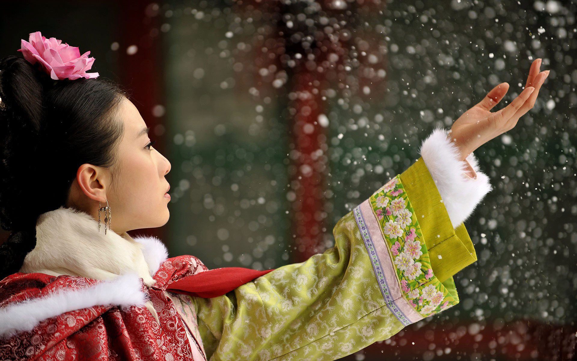 An HD wallpaper featuring a scene from the Asian TV show Scarlet Heart, depicting a woman in traditional attire with a pink flower in her hair, reaching out to falling snowflakes.