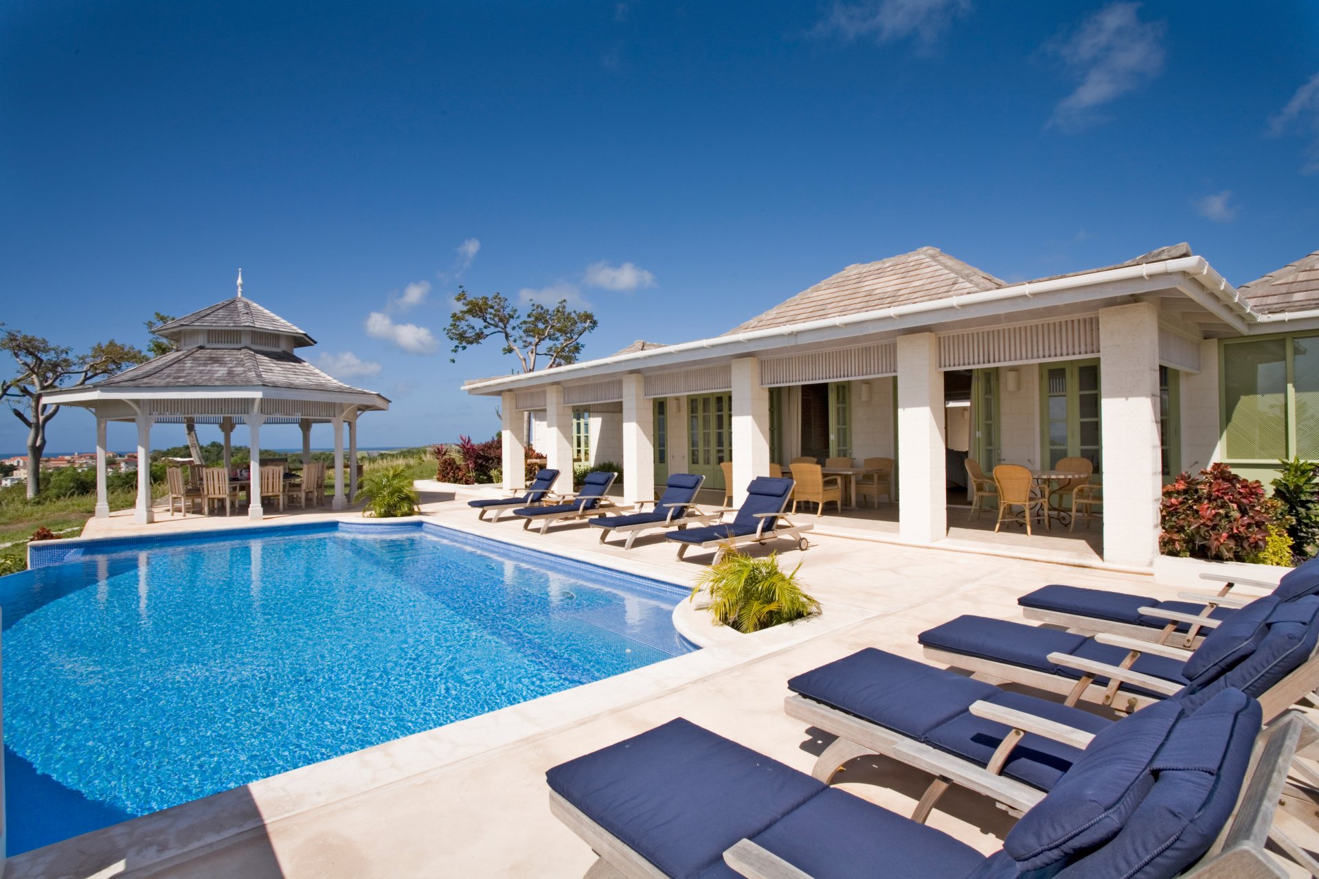 4K Ultra HD desktop wallpaper of a man-made pool beside a modern villa with lounge chairs and a gazebo under a clear blue sky.