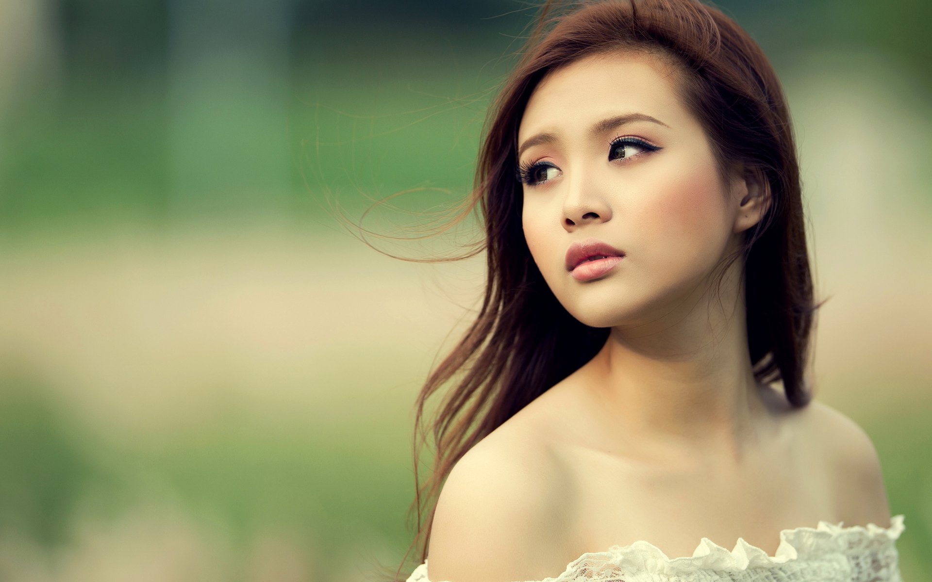 HD desktop wallpaper featuring a woman named Sarah Shuilian, gazing thoughtfully into the distance, with a soft-focused green background enhancing her serene expression.