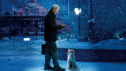 Richard Gere stands in snow, holding a gift, while a Shiba Inu dog gazes up at him in a heartfelt moment from the movie Hachi: A Dog's Tale. A serene winter background adds to the scene.