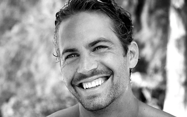 Black and white HD wallpaper featuring a smiling Paul Walker. The image captures the actor's charm and warmth, making it a striking background for any desktop.