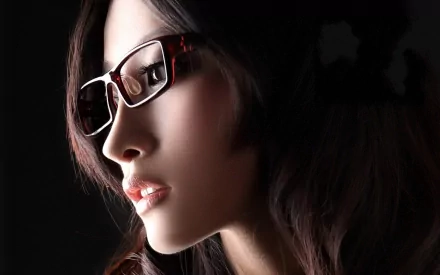 HD desktop wallpaper and background image featuring a woman's face in profile with dark hair and fashionable glasses, set against a dark background.