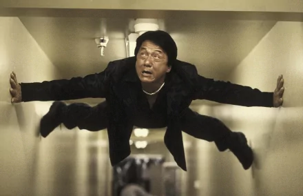 HD wallpaper featuring celebrity Jackie Chan performing a dramatic horizontal split in a narrow hallway, displaying his renowned agility and physical prowess.