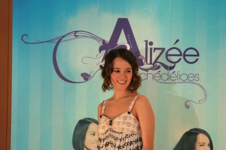 HD PC desktop wallpaper featuring Alizée smiling against a light blue background with music-themed text and decorative swirls.