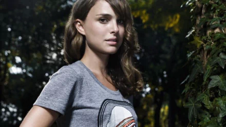 A striking HD wallpaper featuring Natalie Portman, showcasing her in a gray t-shirt, surrounded by lush greenery, capturing a blend of natural beauty and celebrity charm.