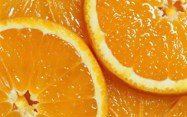 Vibrant close-up of fresh orange slices showcasing their juicy texture. This HD wallpaper features a rich orange color, enhancing any desktop background.
