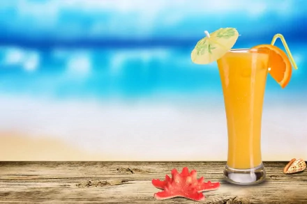 A vibrant orange cocktail with a garnish sits on a wooden surface by the beach, captured in stunning 4K Ultra HD as a PC desktop wallpaper and background.