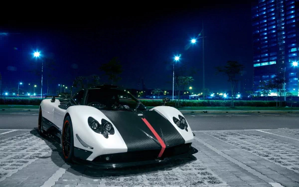 A striking Pagani Zonda parked under night lights, showcasing its sleek design with a white and black color scheme, serves as an impressive HD desktop wallpaper.