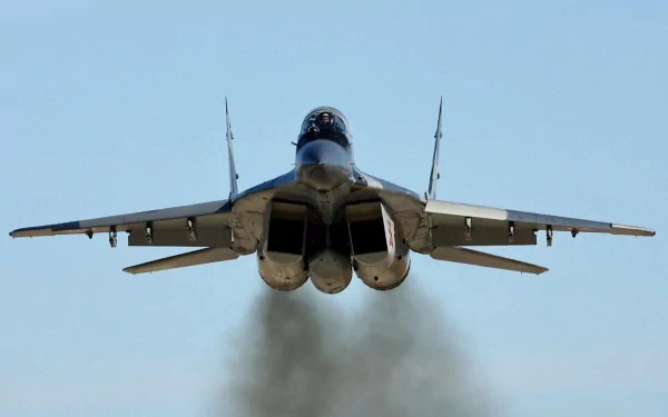A Mikoyan MiG-29 jet fighter takes off, showcasing its powerful engines and military design against a clear blue sky. This HD image serves as a striking desktop wallpaper.