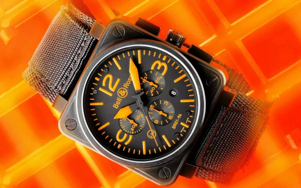 Close-up HD desktop wallpaper of a man-made watch with a black face and orange numerals, set against a vibrant orange geometric background.