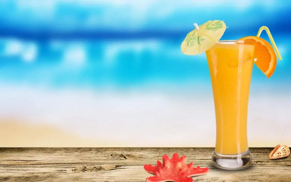 A vibrant orange cocktail with a garnish sits on a wooden surface by the beach, captured in stunning 4K Ultra HD as a PC desktop wallpaper and background.