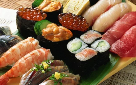HD PC desktop wallpaper showcasing an assortment of colorful sushi, including nigiri, rolls, and gunkan, artfully arranged on a wooden platter.