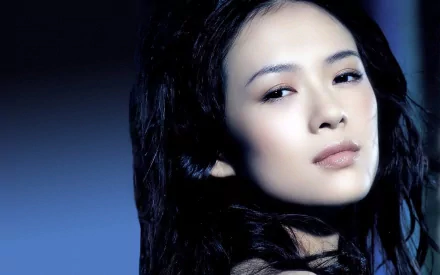 HD PC desktop wallpaper featuring a close-up portrait of celebrity Zhang Ziyi with a serene expression and dark flowing hair against a deep blue background.