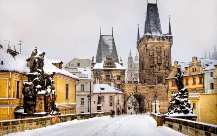 Snowy Prague scene: a man-made stone bridge leading to Gothic castle towers, presented as a 2K Quad HD PC desktop wallpaper background.