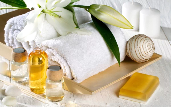 Man-made spa setup with white rolled towels, essential oils, a flower, candles, and soap arranged on a wooden tray, captured in HD for a PC desktop wallpaper.