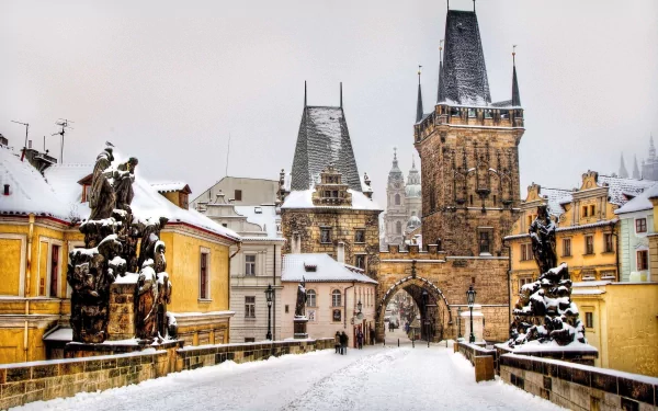 Snowy Prague scene: a man-made stone bridge leading to Gothic castle towers, presented as a 2K Quad HD PC desktop wallpaper background.