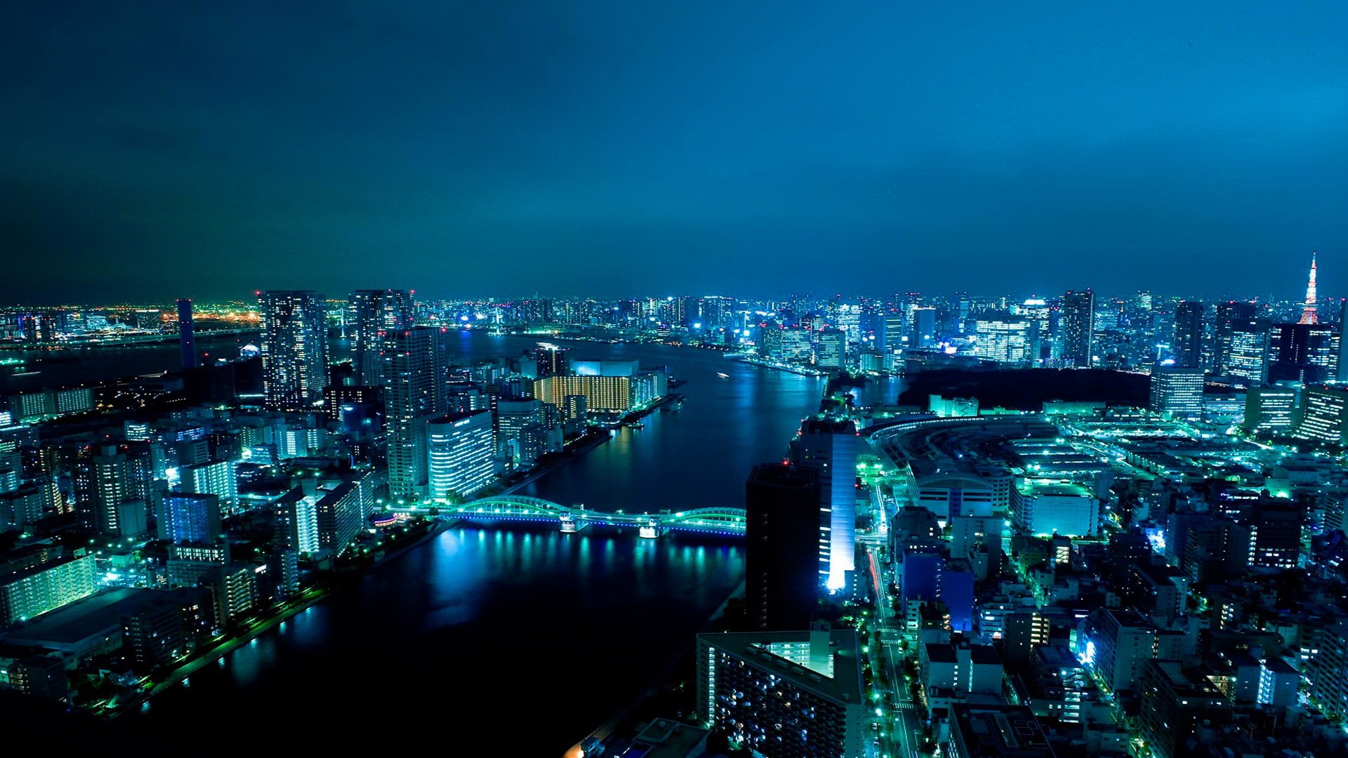 Nighttime aerial view of Tokyo's illuminated cityscape, showcasing the man-made urban expanse along the river in Japan.