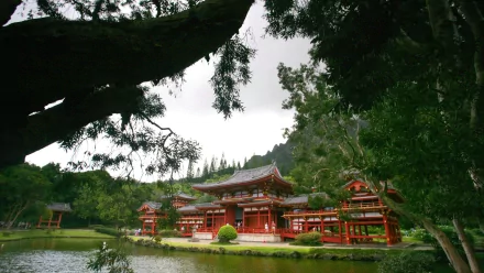 HD desktop wallpaper: Byodo-In temple, red wooden religious shrine beside a reflective pond, framed by trees with a mountain backdrop.