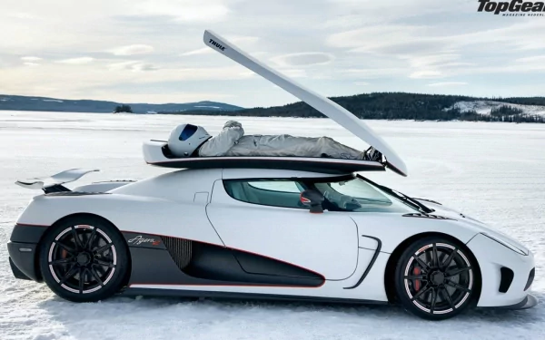 HD wallpaper featuring The Stig from Top Gear standing next to a white sports car with its gull-wing door open on a snowy terrain.