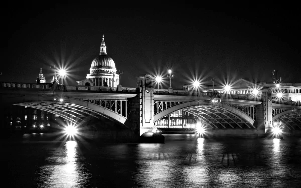 Black and white HD desktop wallpaper of London’s Southwark Bridge illuminated at night with St. Paul’s Cathedral in the background.