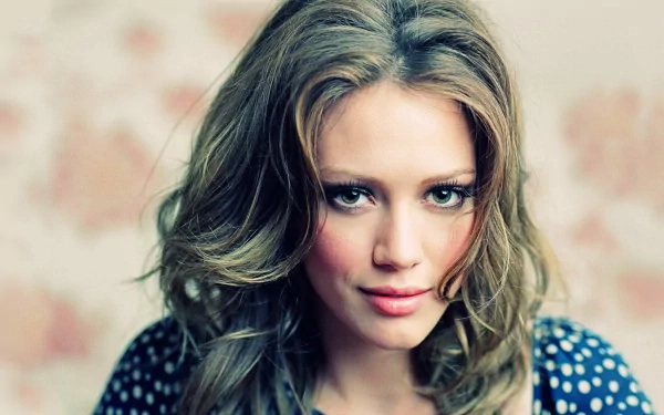 HD PC desktop wallpaper featuring a close-up portrait of celebrity Hilary Duff with soft lighting and a blurred floral background.