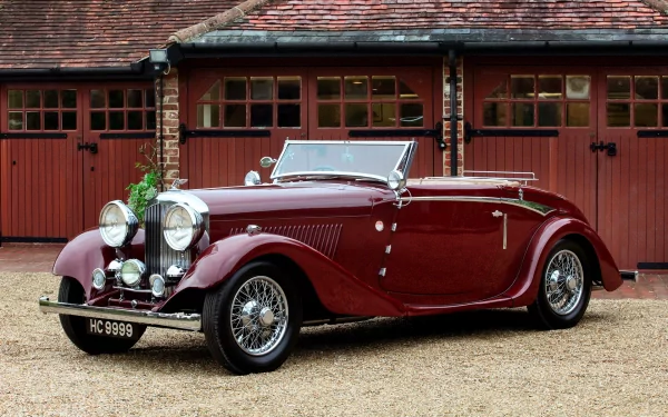 HD desktop wallpaper featuring a classic 1934 Bentley stylish convertible parked in front of vintage red garage doors.
