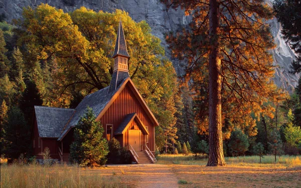 A serene church nestled among vibrant trees, bathed in warm sunlight. This HD desktop wallpaper captures the peaceful essence of nature and spirituality.