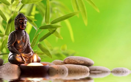 HD desktop wallpaper featuring a serene Buddhist statue, surrounded by stones and green bamboo leaves, exuding tranquility and spirituality.