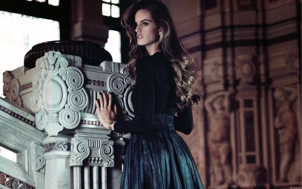 HD PC desktop wallpaper featuring Izabel Goulart posing elegantly by ornate architectural details in a dimly lit setting.