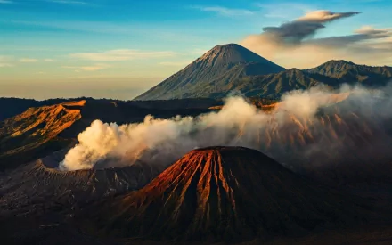 HD desktop wallpaper of Mount Bromo with clouds surrounding the volcanic peaks at sunrise.