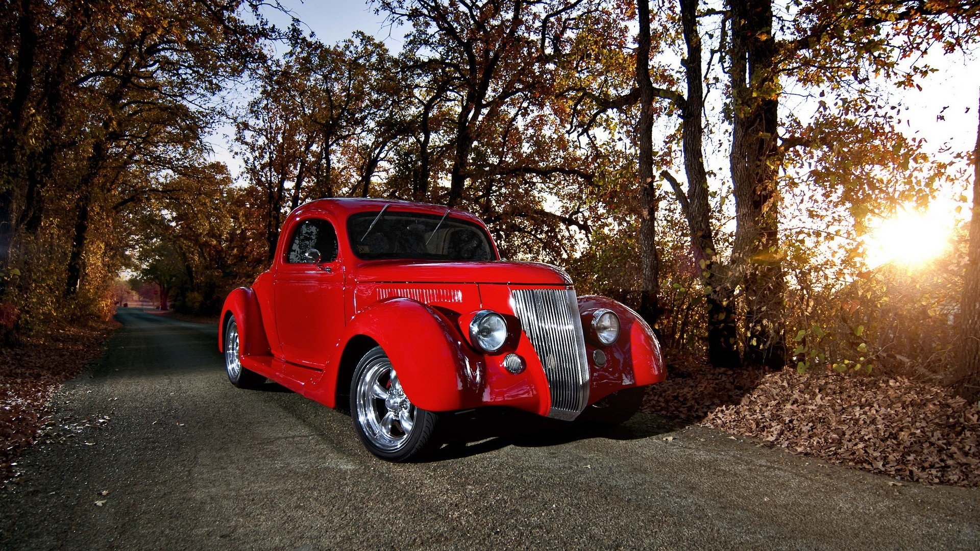 A vibrant red Ford Coupe parked on a tree-lined road at sunset, captured in an HD desktop wallpaper showcasing classic vehicle beauty.