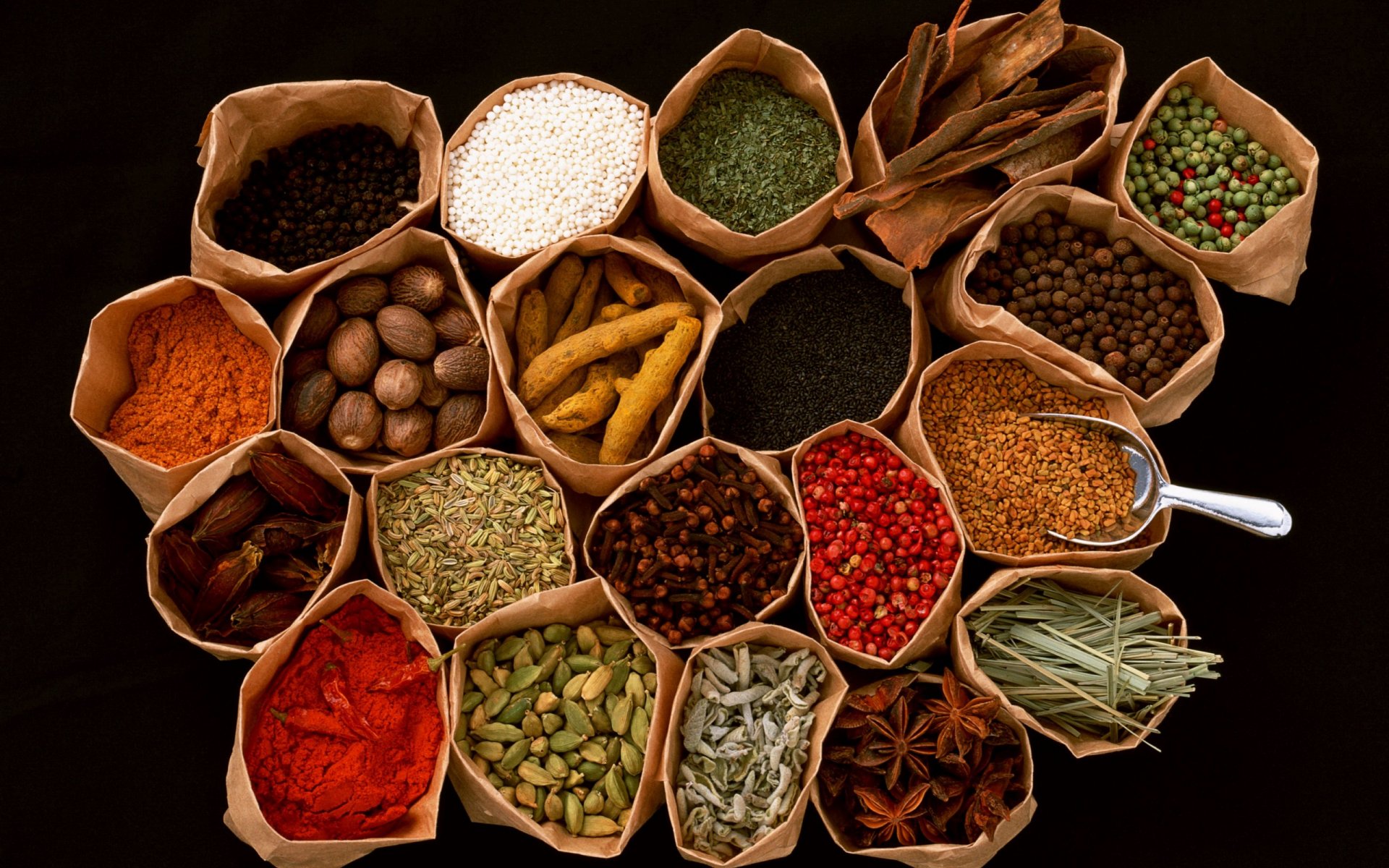HD PC desktop wallpaper featuring an array of colorful herbs and spices arranged in small paper bags on a dark background, highlighting vibrant food ingredients.